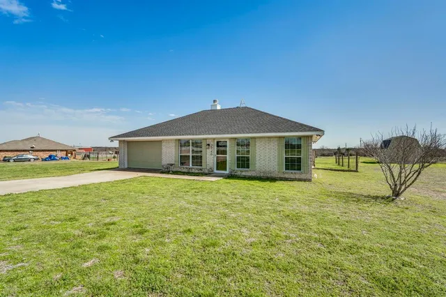 a yellow house with a big yard and large trees