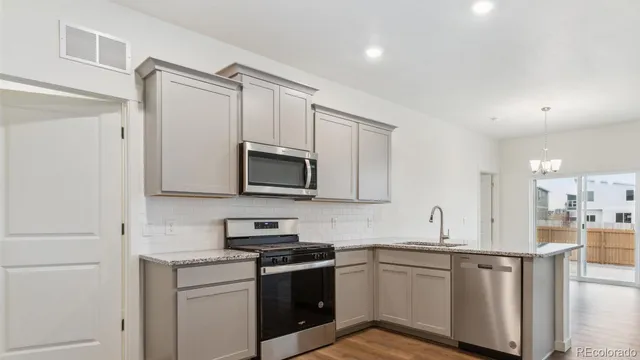 a kitchen with stainless steel appliances granite countertop white cabinets a sink a stove a refrigerator and white cabinets