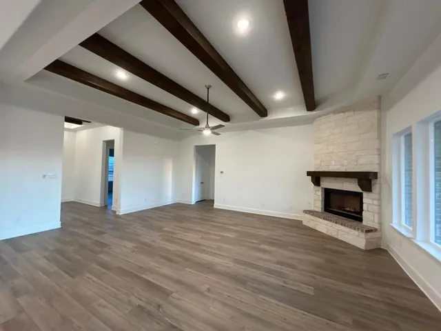 an empty room with wooden floor fireplace and windows