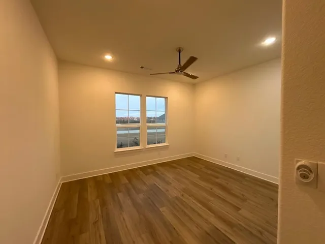 a view of an empty room with a window and wooden floor