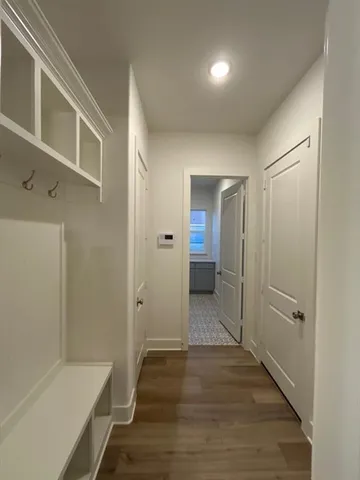 a view of a hallway with wooden floor and a bathroom