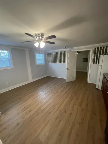 an empty room with wooden floor fan and windows