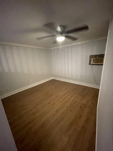 en empty room with wooden floor and fan