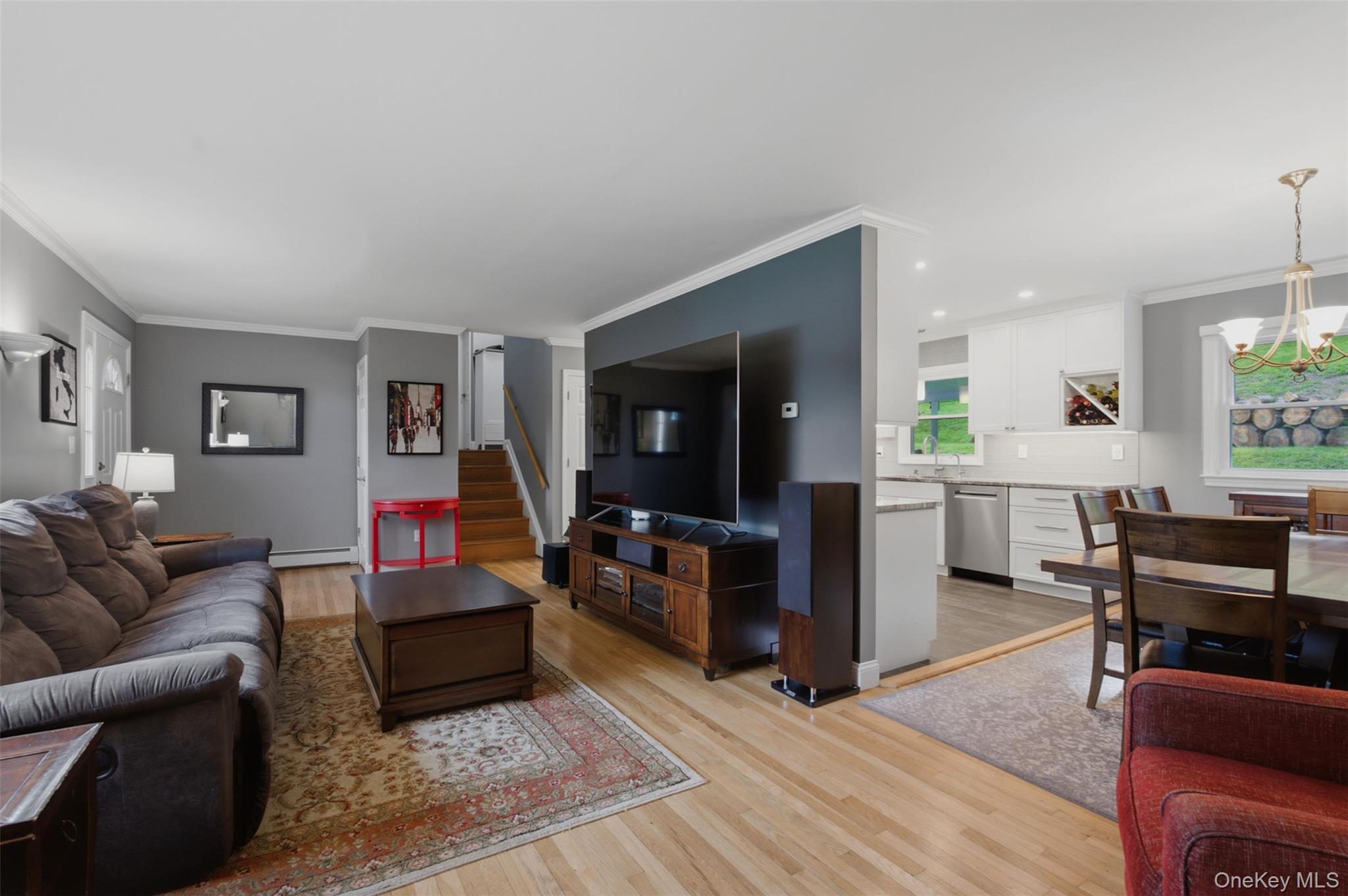 617 Cardinal Road Cortlandt Manor, NY 10567 - Photo 5 of 32 Open-concept living area featuring light wood-finish flooring, white crown molding, and a partial wall separating living and kitchen areas