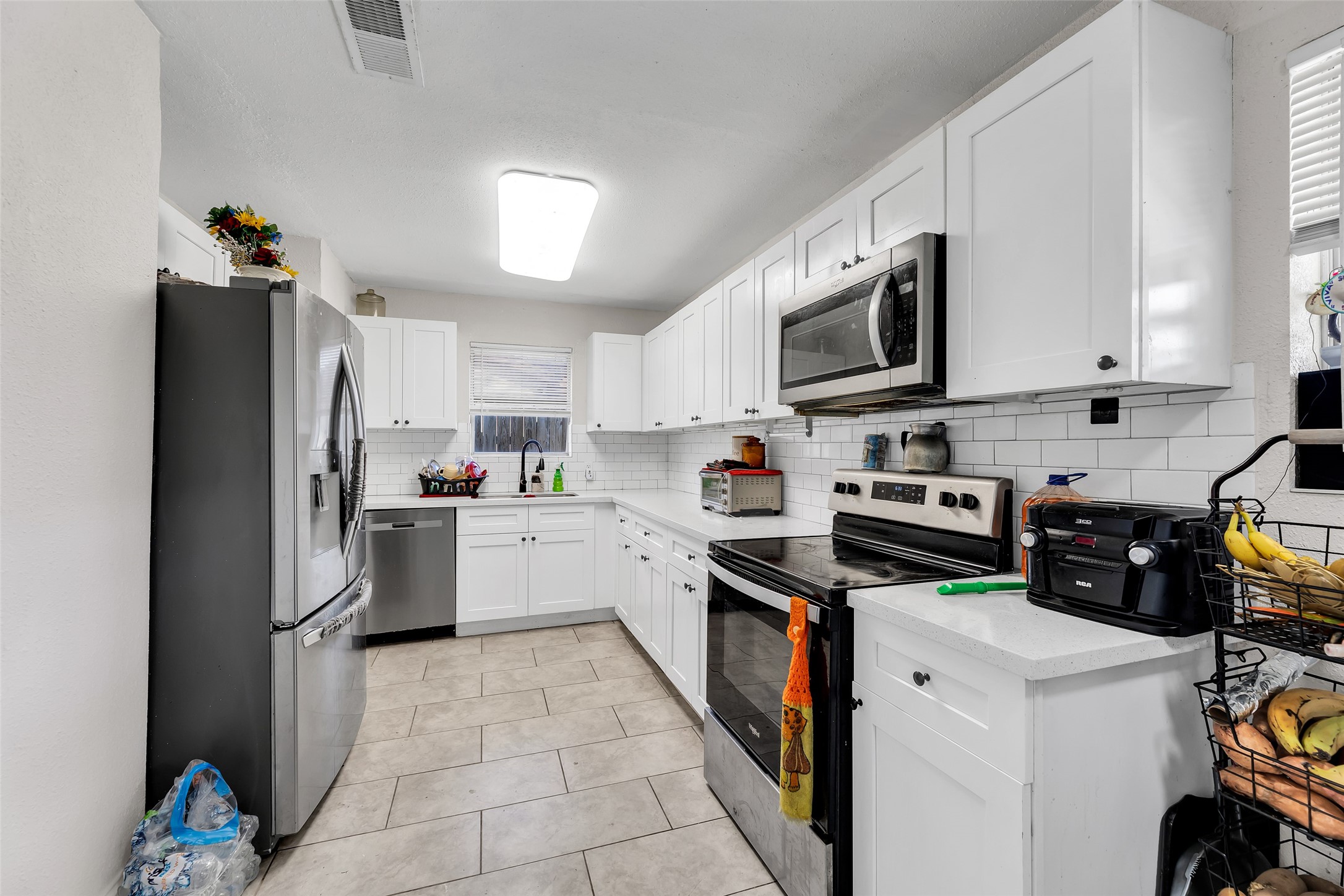 819 Hackberry Street Stafford, TX 77477 - Photo 4 of 23 a kitchen with granite countertop a refrigerator a stove top oven a sink dishwasher and white cabinets with wooden floor
