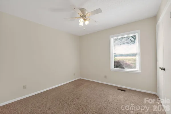 an empty room with windows and chandelier fan