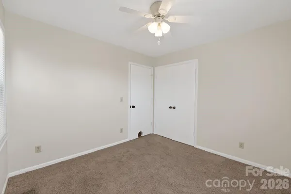 an empty room with a ceiling fan and window