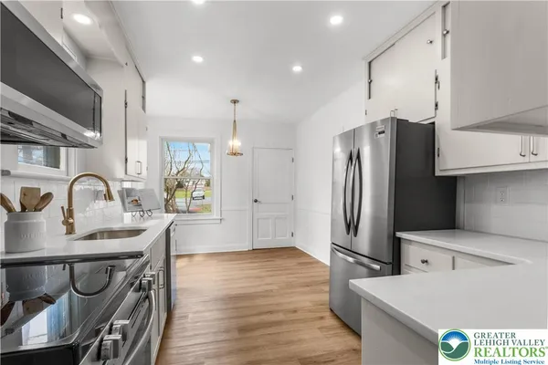 a kitchen with stainless steel appliances granite countertop a refrigerator a stove and a sink with wooden floor