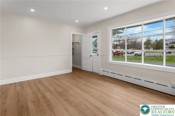 a view of an empty room with wooden floor and a window
