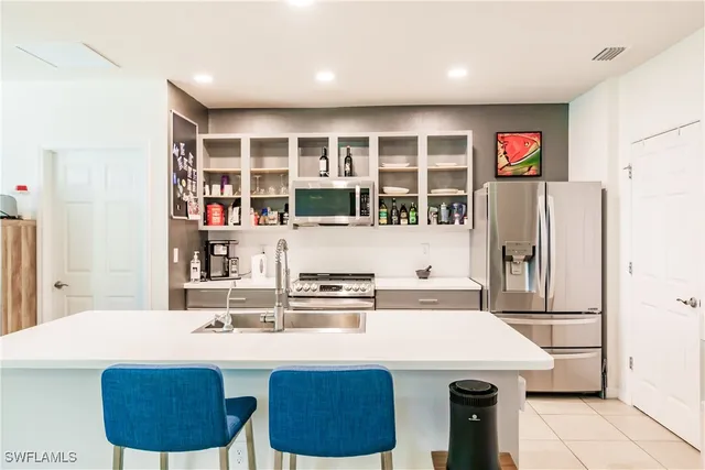 a kitchen with stainless steel appliances granite countertop a sink a stove a refrigerator and white cabinets