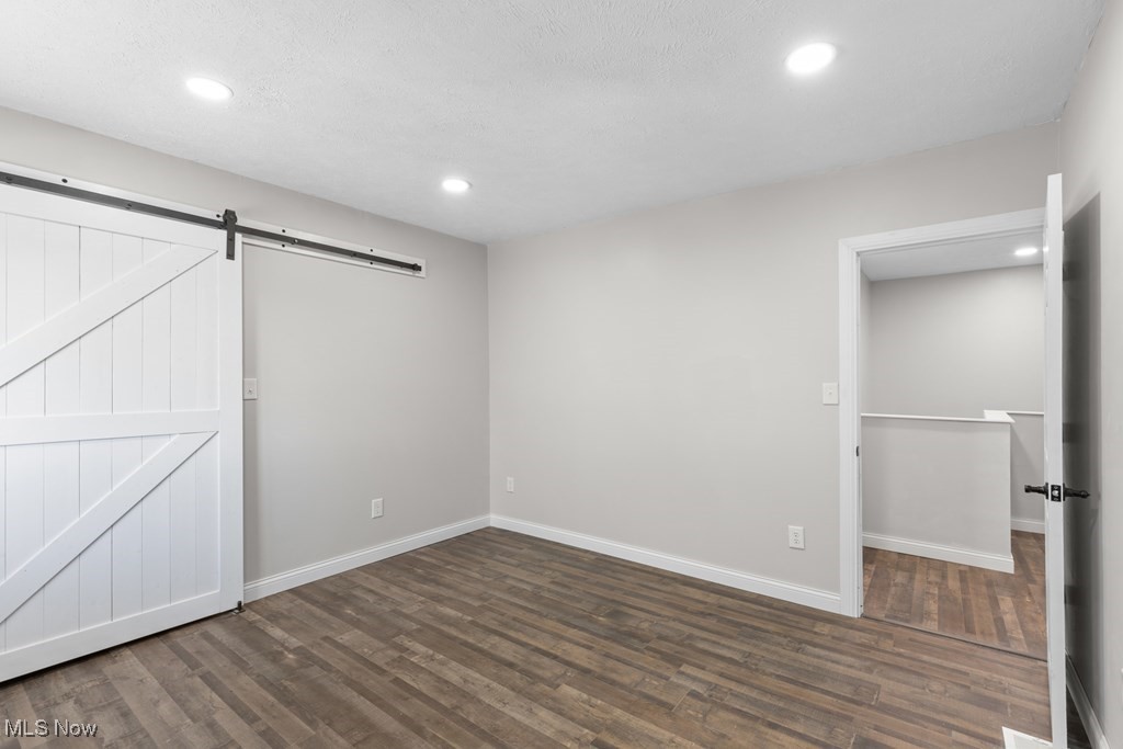139 Patterson Road Weirton, WV 26062 - Photo 21 of 46 Unfurnished bedroom featuring dark wood-style flooring, recessed lighting, and a barn door