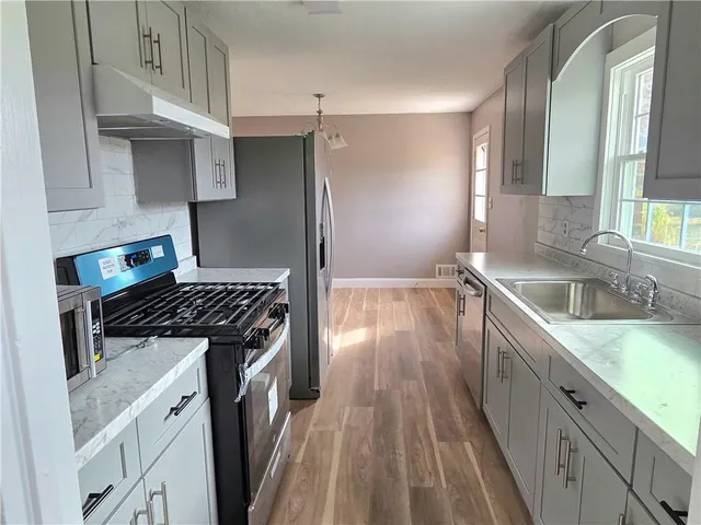 a kitchen with granite countertop a sink stove and refrigerator
