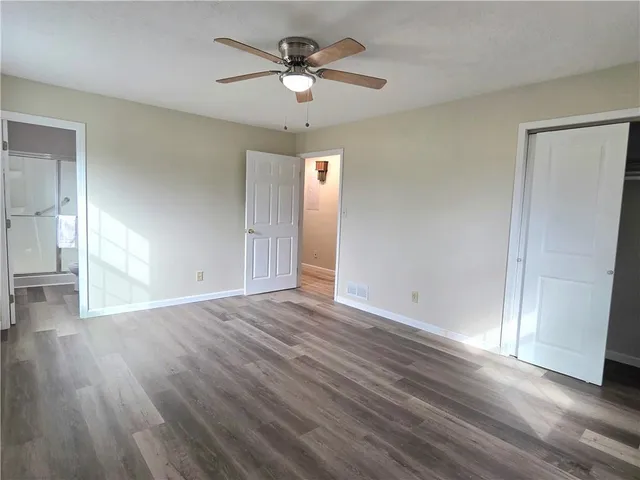an empty room with wooden floor and a ceiling fan
