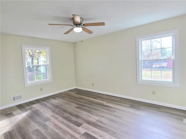 a view of empty room with wooden floor and fan