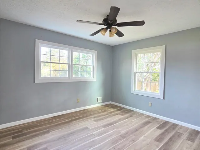 a view of empty room with wooden floor and fan