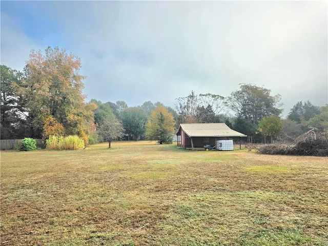 a house with a field with trees in the background