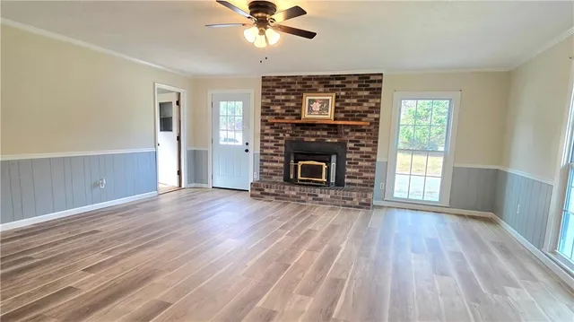 an empty room with wooden floor fireplace and windows