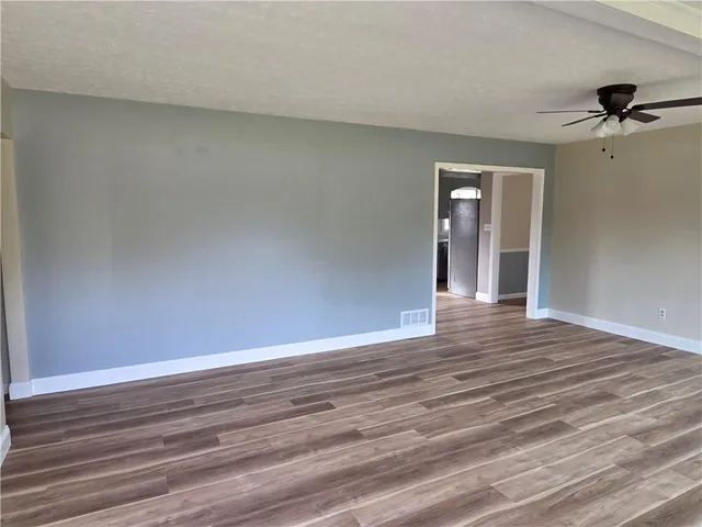 a view of a livingroom with wooden floor and a ceiling fan