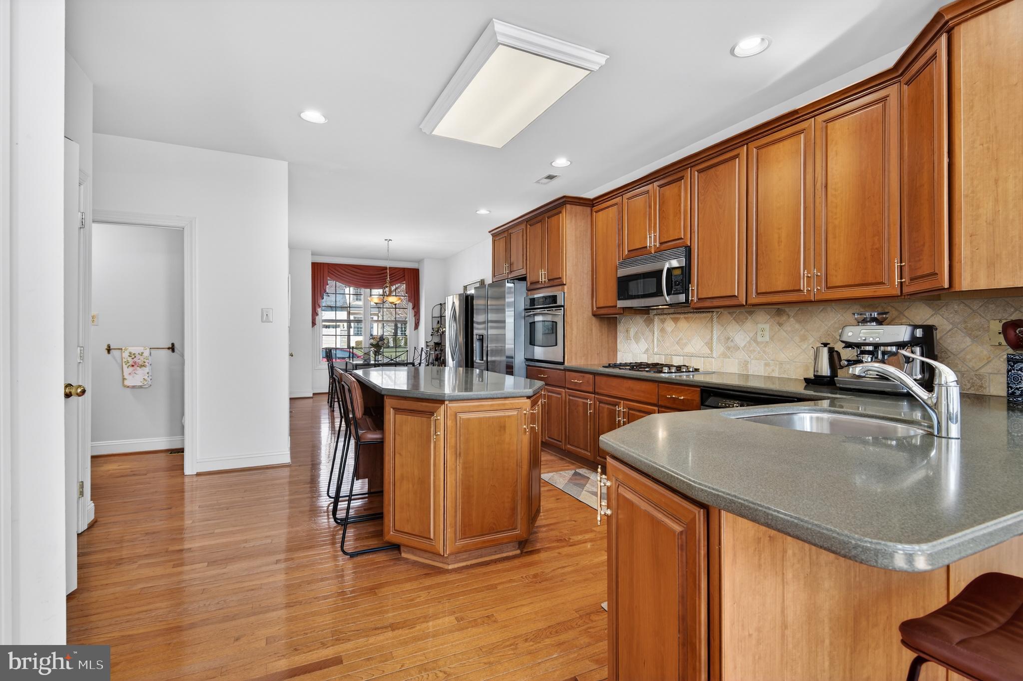 98 Granville Way Exton, PA 19341 - Photo 12 of 35 a kitchen with granite countertop a stove a sink a refrigerator and blue cabinets with wooden floor