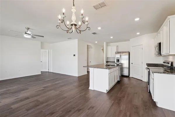 a large kitchen with kitchen island a stove a sink a center island and wooden floor