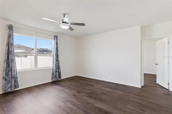 an empty room with wooden floor cabinet and windows