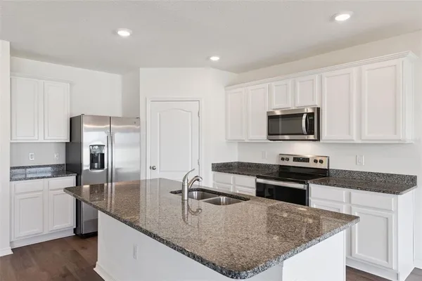 a kitchen with granite countertop a stove sink and microwave