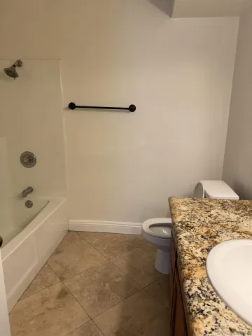 a bathroom with a granite countertop toilet and a bathtub