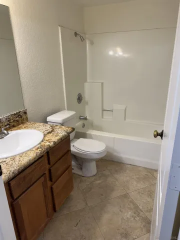 a bathroom with a granite countertop sink a toilet a mirror and shower