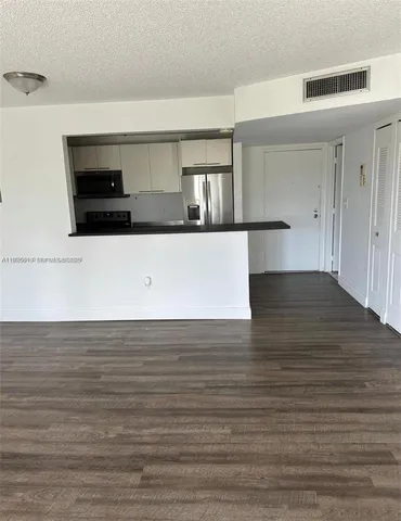 a view of kitchen and empty room with wooden floor