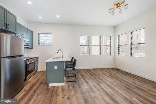 a kitchen with stainless steel appliances granite countertop a refrigerator a sink dishwasher a stove and white countertops with wooden floor