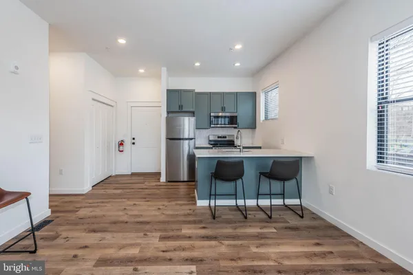 a kitchen with kitchen island a counter top space a sink stainless steel appliances and cabinets
