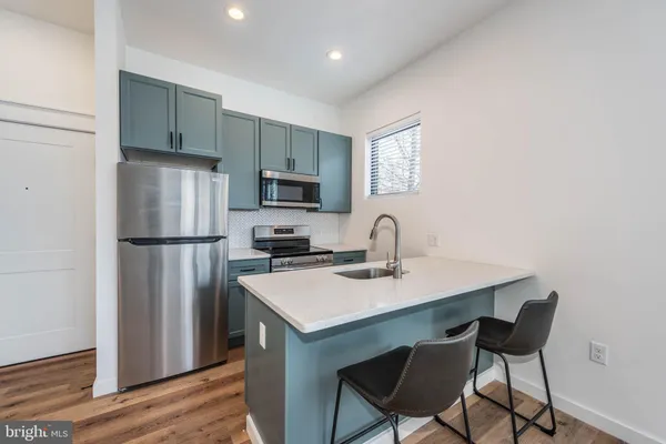 a kitchen with stainless steel appliances granite countertop a refrigerator a sink a stove a microwave and dining table