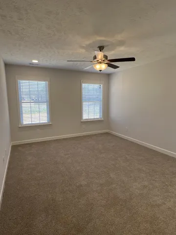 an empty room with windows and chandelier fan