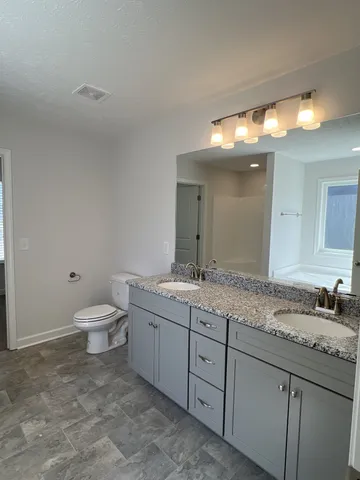 a bathroom with a granite countertop sink a toilet and a mirror