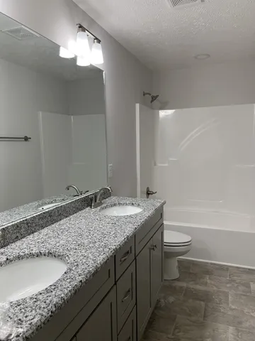 a bathroom with a granite countertop sink a toilet and bathtub