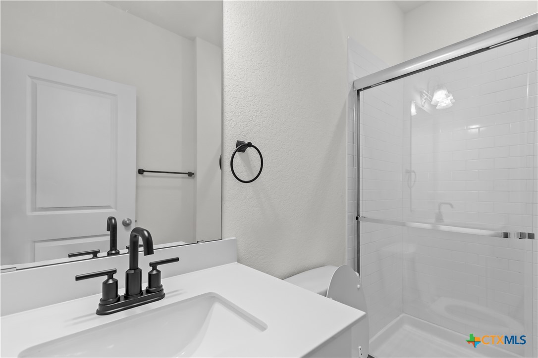 430 Line Of Fire Way Jarrell, TX 76537 - Photo 17 of 28 a bathroom with a sink a mirror and a shower