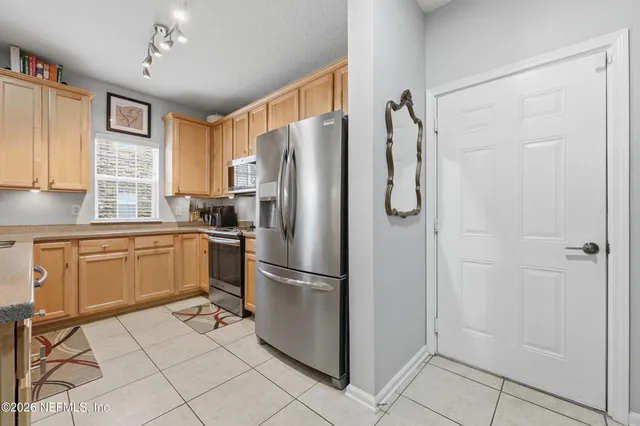 a kitchen with granite countertop a sink stainless steel appliances white cabinets and a window