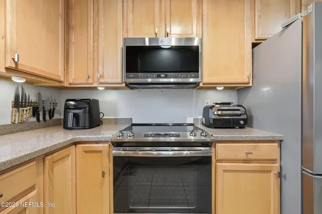 a kitchen with granite countertop white cabinets stainless steel appliances and a window