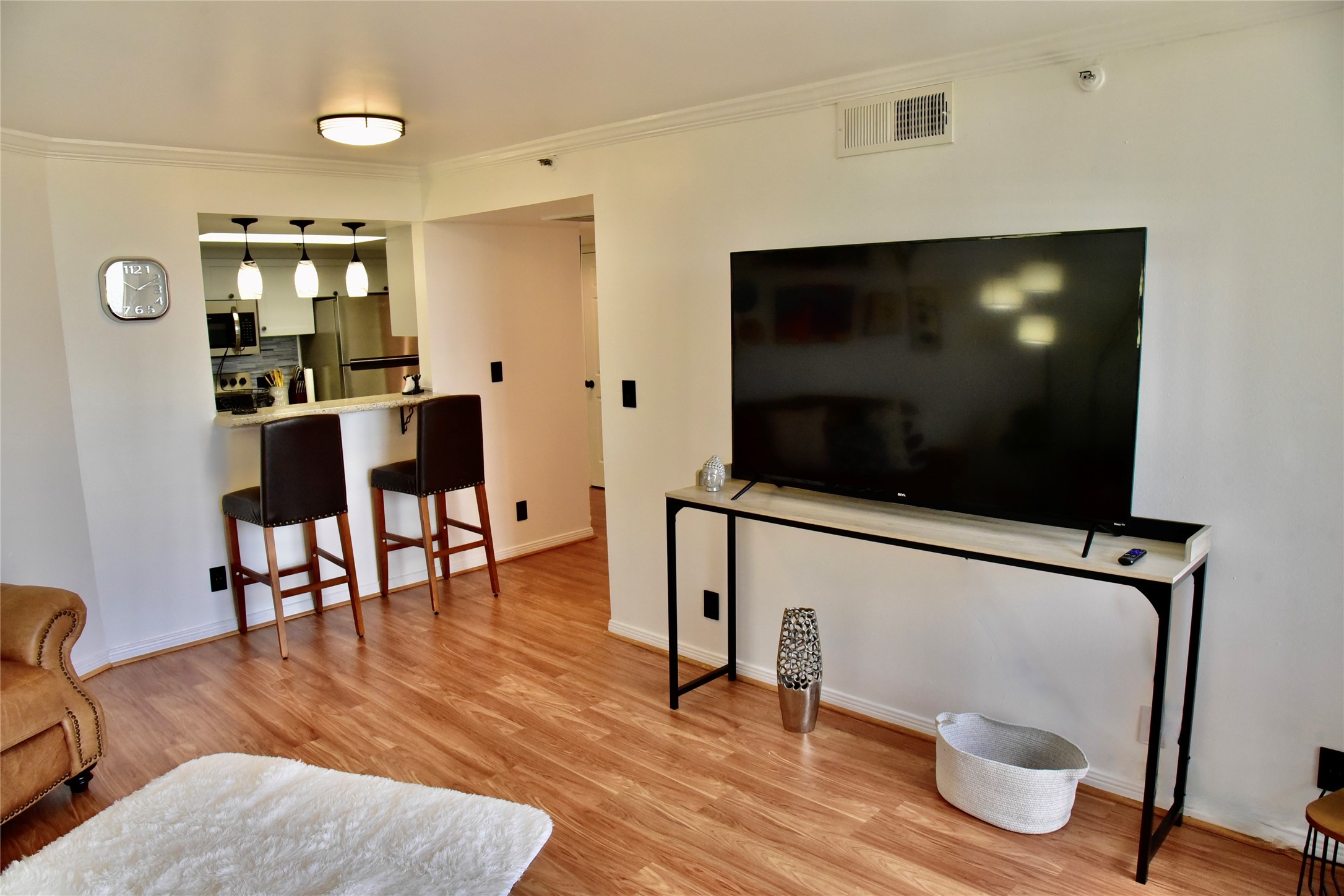 3525 Sage Road, Unit 701 Houston, TX 77056 - Photo 3 of 48 Bright and modern living space featuring an open-plan layout that includes a kitchen with a breakfast bar and pendant lighting. The room is equipped with a large flat-screen TV, comfortable and inviting atmosphere.