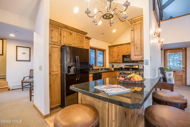 a kitchen with stainless steel appliances a dining table chairs and refrigerator