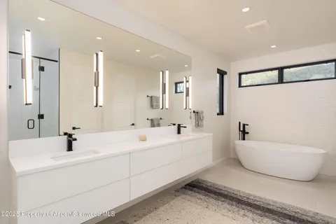 a bathroom with a double vanity sink mirror and bathtub