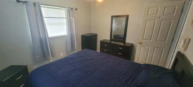 a bedroom with a bed and a flat tv screen on dresser