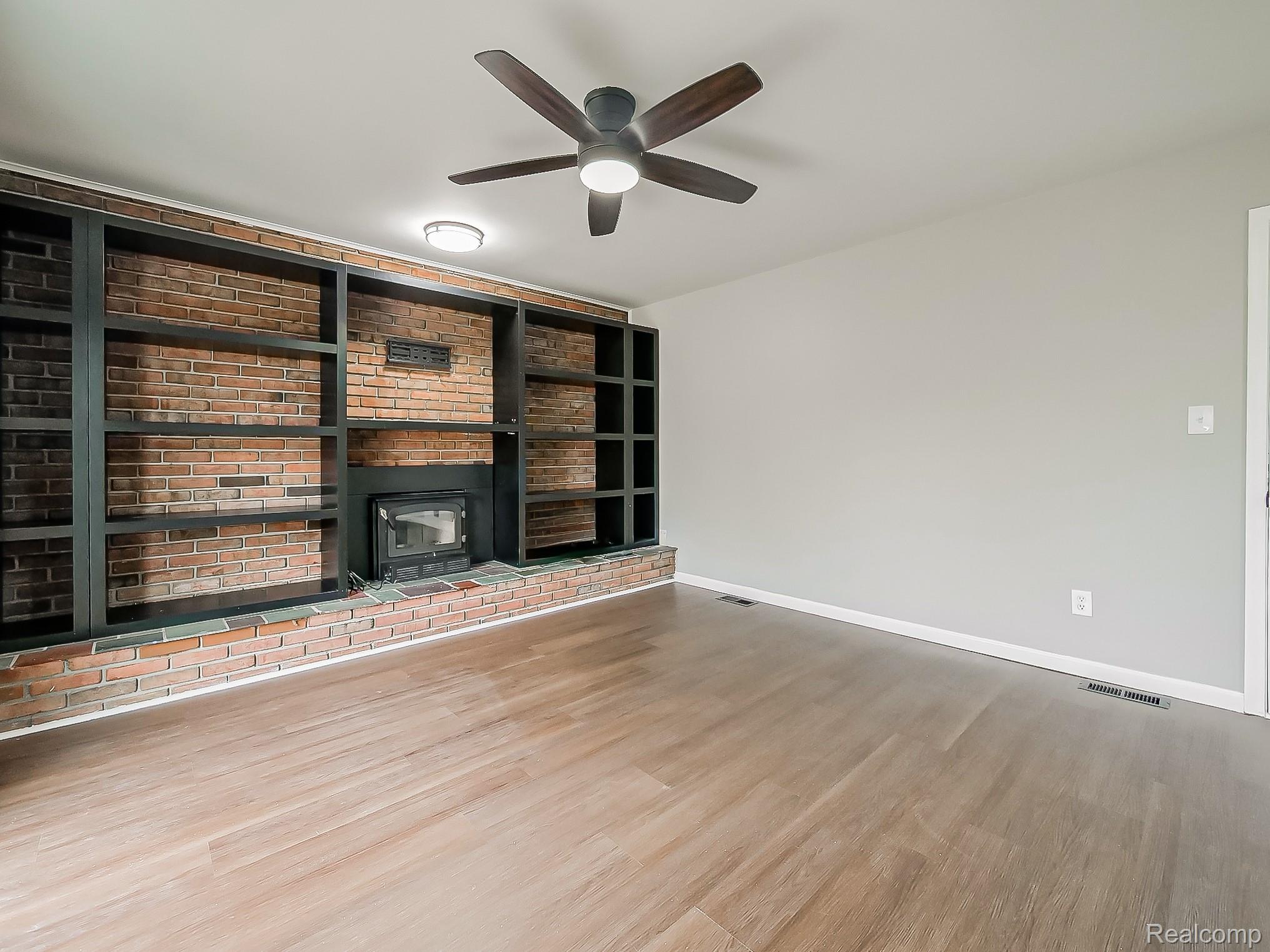 11780 Haggerty Road Belleville, MI 48111 - Photo 6 of 41 Unfurnished living room with built in shelves, light wood-style floors, and a ceiling fan