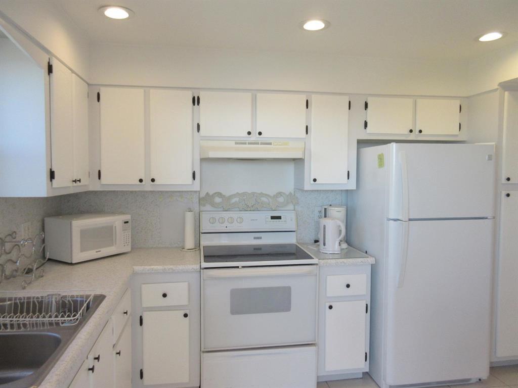 1200 Hibiscus Avenue, Unit 801 Pompano Beach, FL 33062 - Photo 3 of 12 a kitchen with white cabinets and white appliances