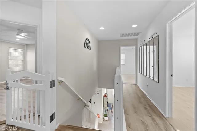 a view of an empty room with wooden floor and a ceiling fan