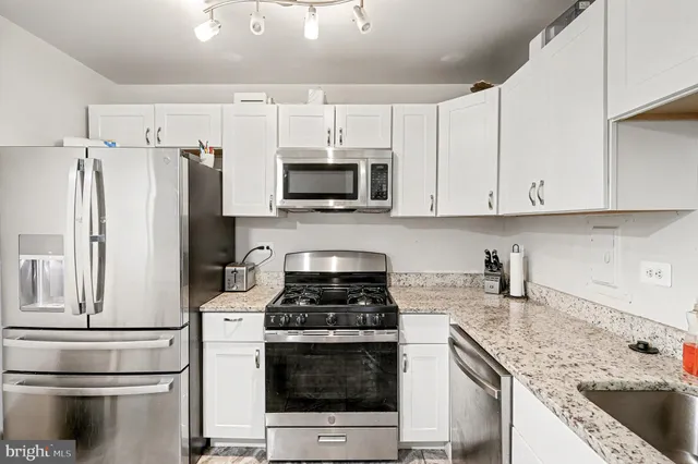 a kitchen with granite countertop a sink stove and refrigerator