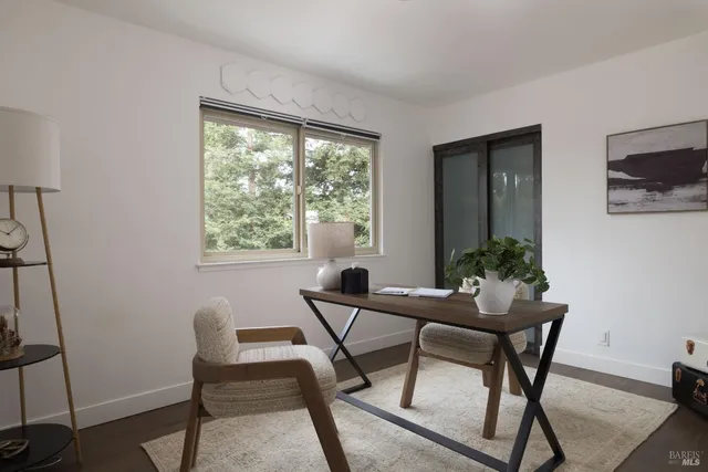 a view of a workspace room with furniture and window