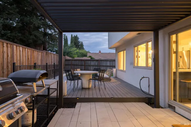 a view of a patio with table and chairs with wooden floor and fence
