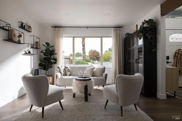 a living room with furniture large window and potted plants