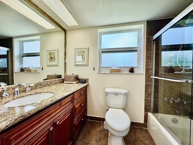 a bathroom with a granite countertop toilet a sink and a bathtub
